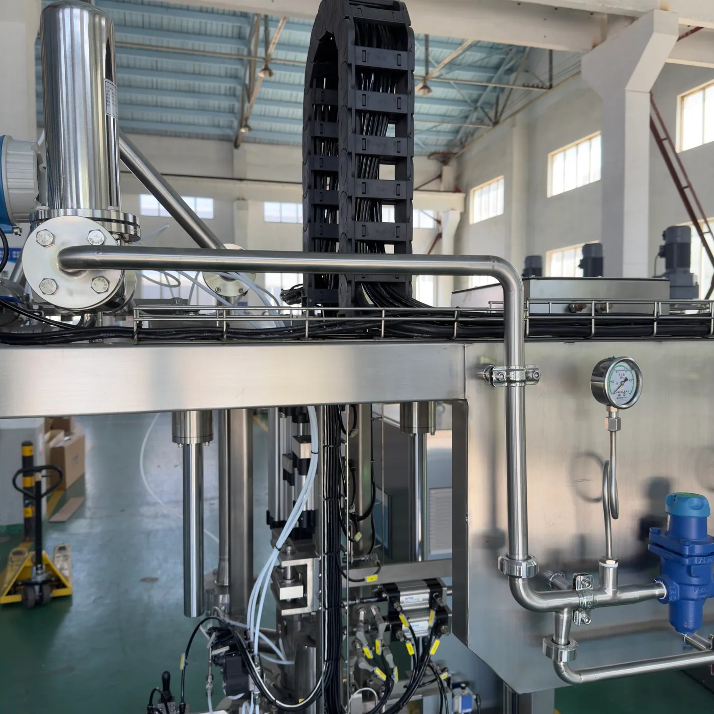 Close-up of a stainless filling head, pressure gauge and product piping